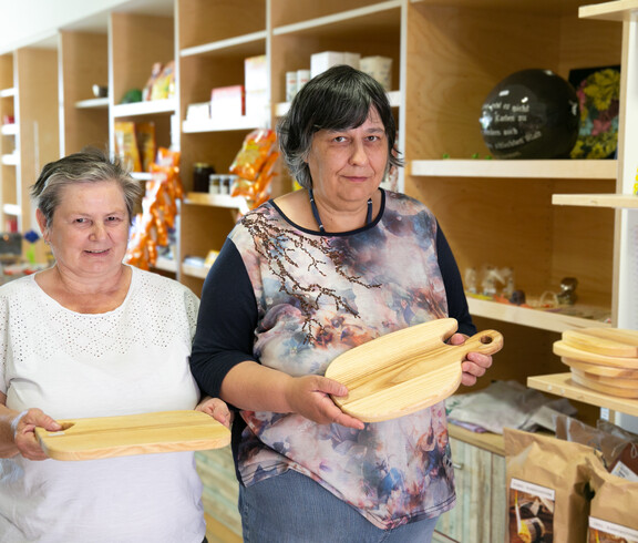 Zwei Frauen halten selbst gemachte Holz-Jausen-Brettl in die Kamera.