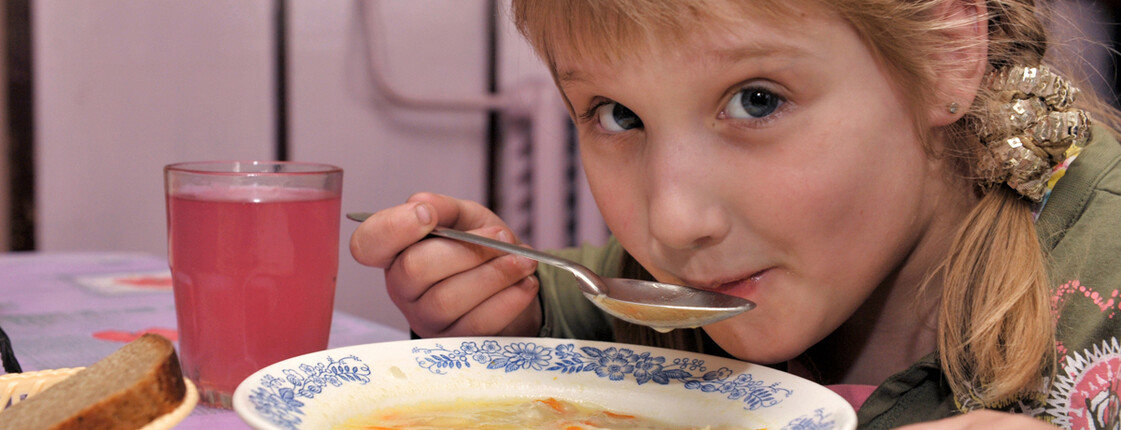 Ein Bub löffelt Suppe.