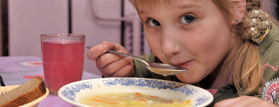 Ein Bub löffelt Suppe.