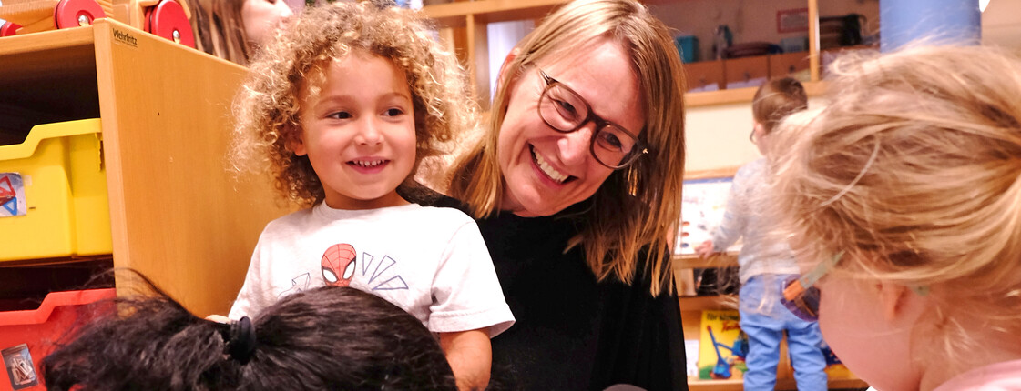 Eine Pädagogin spielt mit drei Kindern.