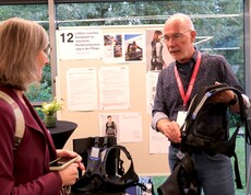 Ein Mann hält eine spezielle Weste in der Hand und erklärt einer Frau etwas darüber.