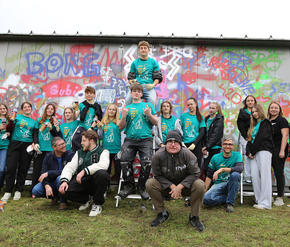 Eine Gruppe von Jugendlichen vor einer Wand mit Grafitti