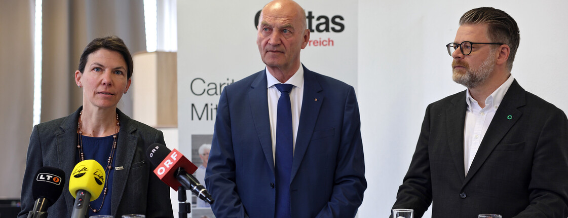 Drei Personen stehen an einem Rednerpult.