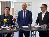 Drei Personen stehen an einem Rednerpult.