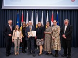 Ein Gruppenfoto mit mehreren Menschen und in der Mitte steht der Preisträger mit einer Urkunde in der Hand.