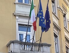 Eine Hauswand wo auf einem Balkon drei Flaggen wehen.