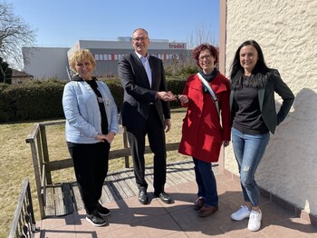 Am Foto v. li.: Caritas-Flüchtlingsbetreuerin Nadja Meissner, TroGroup CEO Norbert Schrüfer sowie die Leiterin Lisa Steinkogler und die Regional-Leiterin Veronika Zweimüller von der Flüchtlingshilfe der Caritas OÖ. Ein Mann und eine Frau übergeben vor einem Haus einen Schlüssel an zwei Frauen