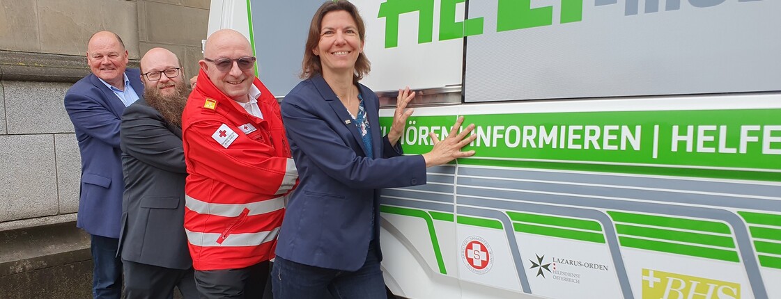 Vier Personen stehen vor einem Bus.