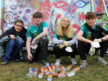 Vier Jugendliche hocken vor Spraydosen, dahinter ist eine Graffiti-Wand.