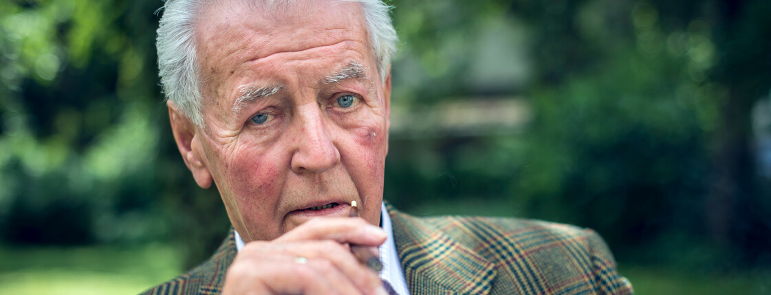 Portrait eines im Garten sitzenden und rauchenden Mannes