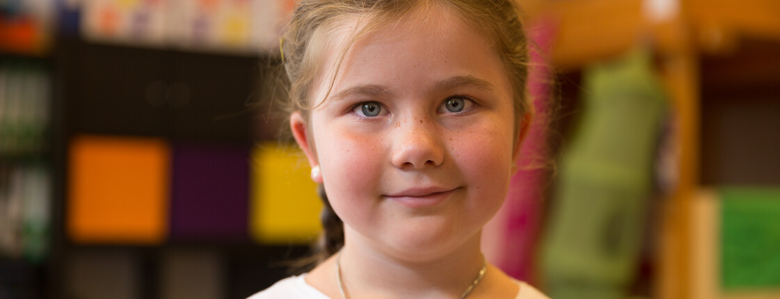 Portrait eines Mädchens mit einer Halskette in einem Kindergarten.