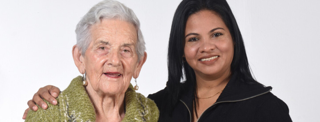 Eine junge Frau legt den Arm um die Schultern einer älteren Frau.