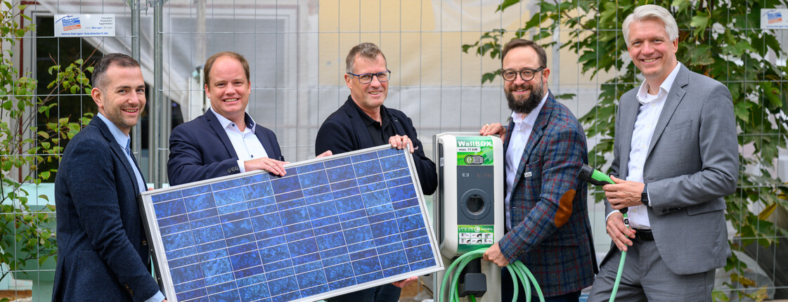 fünf Männer stehen nebeneinander und halten ein Photovoltaik-Panel vor sich
