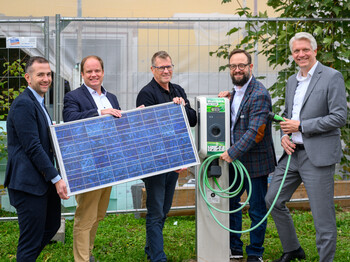 fünf Männer stehen nebeneinander und halten ein Photovoltaik-Panel vor sich