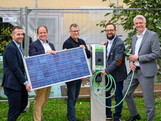 fünf Männer stehen nebeneinander und halten ein Photovoltaik-Panel vor sich