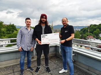 Zwei junge Männer der Musikgruppe „BluntKartell“ übergeben einen Spendencheck in Höhe von 310 Euro an Caritas-Mitarbeiter Andreas Falkner