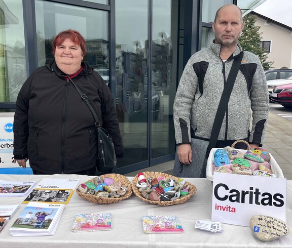 Zwei Personen mit Steinen und Caritas-Sackerl