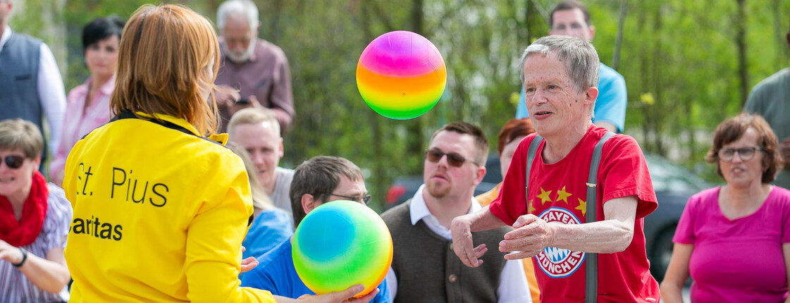 Bunte Menschenmenge, zwei Leute spielen mit zwei bunten Bällen