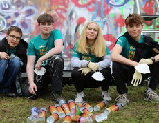 Vier Jugendliche in der Hocke vor einem Grafitti