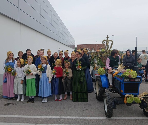 Viele Menschens stehen links im Bild, rechst ist ein alter Tracktor von vorne zu sehen