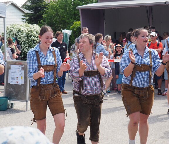 Zwei Männer und eine Frau tanzen in der Lederhosen