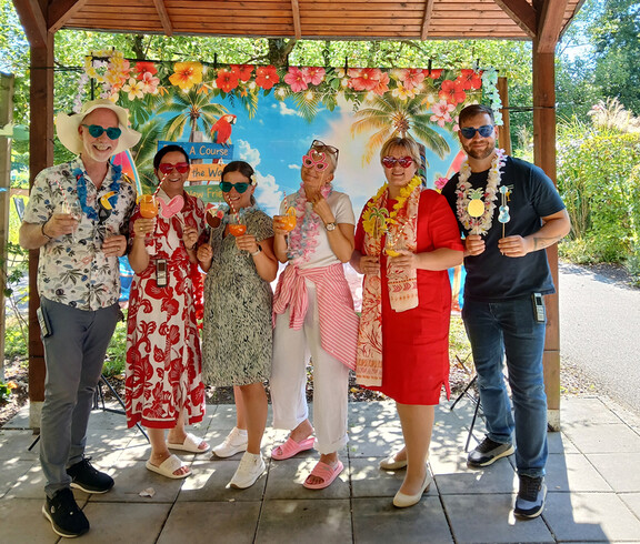 Eine Gruppe von Menschen posiert vor einem Sommerplakathintergrund.