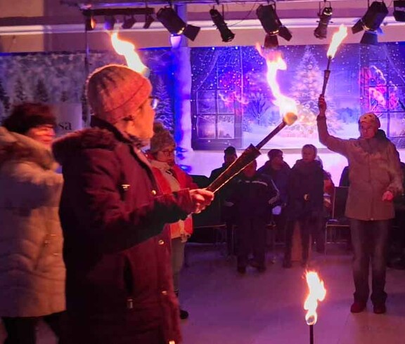 Mehrere Menschen jonglieren mit brennenden Fackeln.