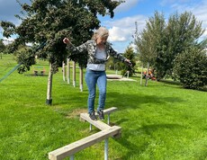 Frau balanciert über Holzstange
