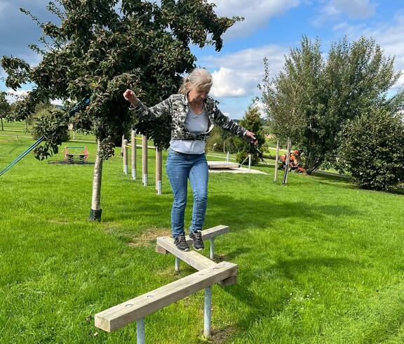 Frau balanciert über Holzstange