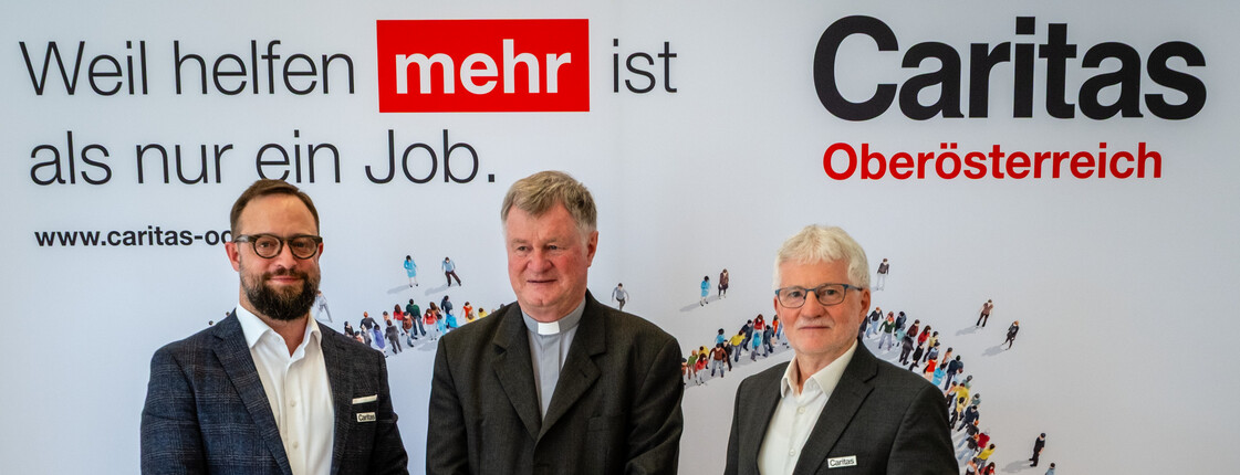 Drei Männer stehen vor einem Werbeplakat