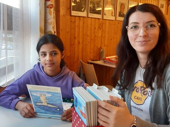 Freiwillige wie Yvonne Wituschek begleiten im Lerncafé die Kinder dabei, Perspektiven und Talente zu entwickeln. Eine Frau und ein Mädchen sitzen an einem Tisch und lernen.