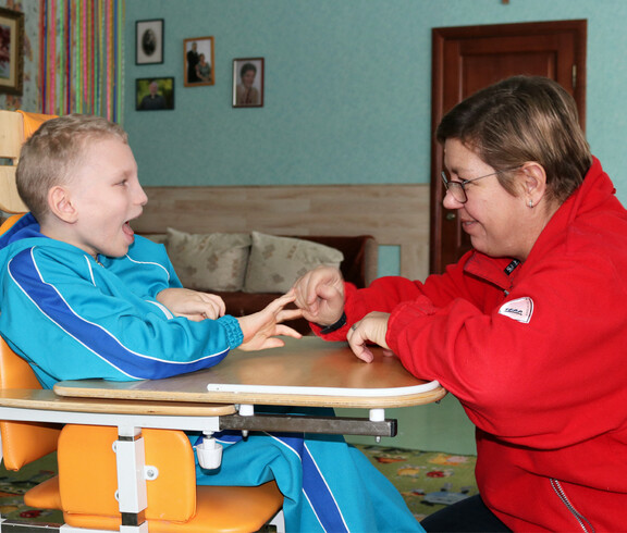 Eine Betreuerin spielt mit einem Kind im Kinderdorf Gomel und unterstützt es bei einer interaktiven Aktivität.