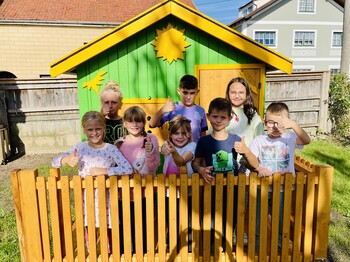 Kinder stehen vor einem Gartenspielhäusen