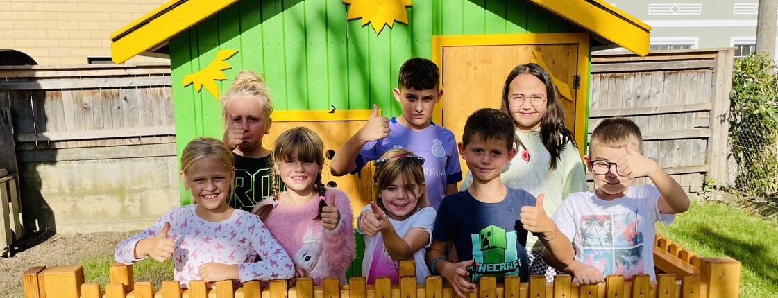 Kinder stehen vor einem Gartenspielhäusen