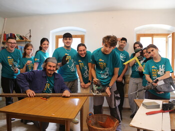 "72 Stunden ohne Kompromiss" zeigten Schülerinnen und Schüler in über 30 sozialen Projekten in ganz OÖ. Foto: Sandra Schindler ein Mann sitzt am Tisch und eine Gruppe Jugendlicher steht hinter ihm
