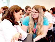 Zwei Frauen sitzen im Saal und unterhalten sich.