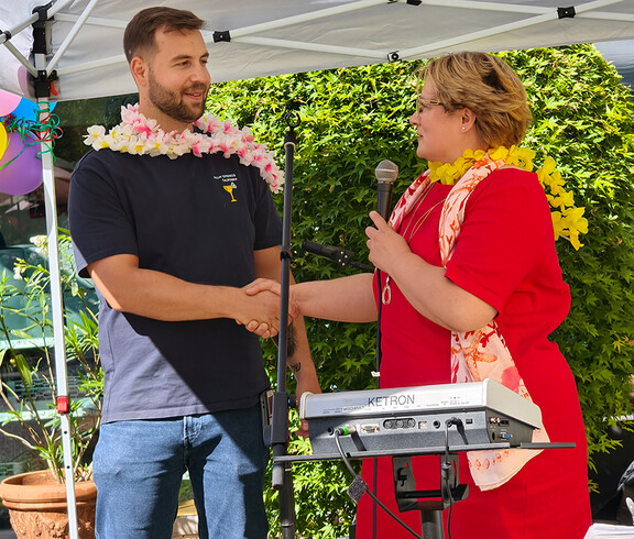 Frau im roten Kleid gibt Mann im dunklen T-Shirt die Hand