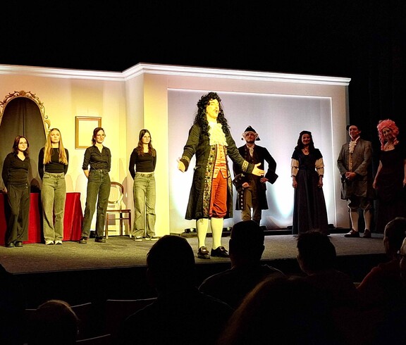 Ein Sprecher im Kostüm - mehrere Personen auf der Bühne