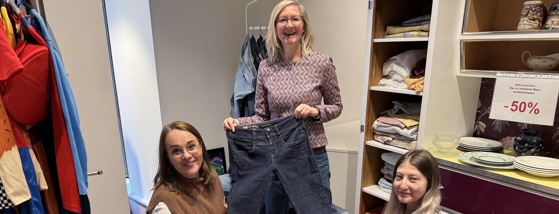 Drei Mitarbeiterinnen des Carla Shops Linz halten eine Jeans hoch.