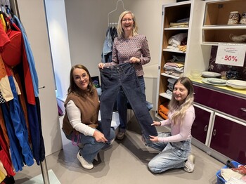 Drei Mitarbeiterinnen des Carla Shops Linz halten eine Jeans hoch.