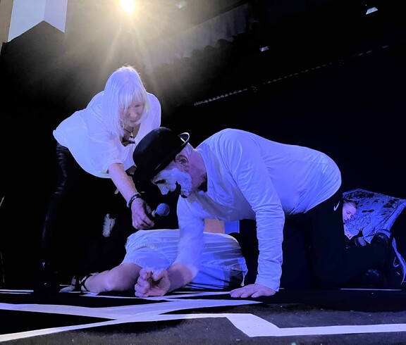 Zwei Schauspieler liegen auf dem Boden, eine dritte Person hat ein Mikro