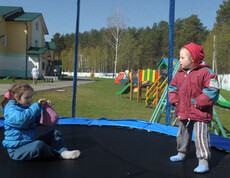 Kinder spielen auf dem Spielplatz im Kinderdorf Gomel, umgeben von Spielgeräten und einer sicheren Umgebung.