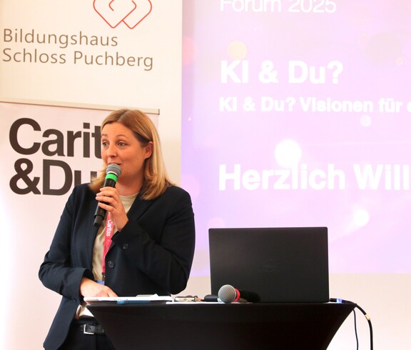 Caritas Präsidentin spricht auf der Bühne in ein Mikrofon.