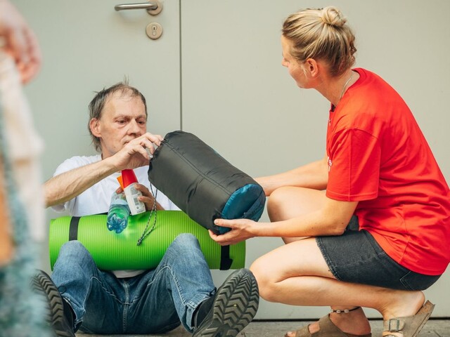 Eine Caritas-Mitarbeiterin teilt ein Hitzepaket an eine obdachlose Person aus.