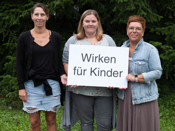 Am Foto v. li.: Die neuen Pfarrcaritas-Kindergartenleiterinnen im Bezirk Gmunden: Alexandra Hametner in Traunkirchen, Michelle Scheichl in St. Wolfgang und Beatrice Kastenhuber in Roitham. Fotocredit: Kienberger Drei Frauen halten ein Schild mit der Aufschrift: Wirken für Kinder