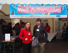 Zwei Personen stehen vor einem Pagodenzelt vor einem Banner. 