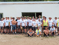 Gruppenfoto von ca. 30 Personen vor dem Rohbau eines Hauses.