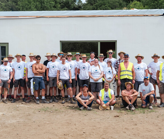 Gruppenfoto von ca. 30 Personen vor dem Rohbau eines Hauses.
