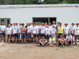 Gruppenfoto von ca. 30 Personen vor dem Rohbau eines Hauses.