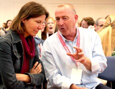 Eine Frau und ein Mann sitzen auf Sesseln und unterhalten sich.